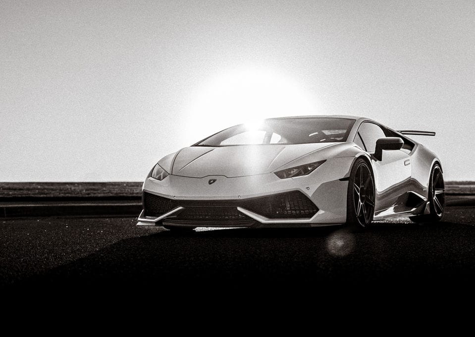 White Lamborghini Huracán in black and white, the sun burning directly behind it